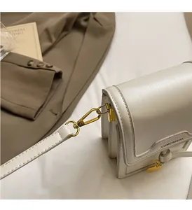 Close-up of cream crossbody bag featuring glossy leather and elegant gold hardware details