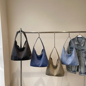 Vintage-Schultertaschen aus Denim in vier Farben an einem minimalistischen Ständer