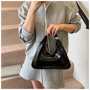 Detail shot of black glossy patent leather bag with silver metal ball clasp and chain