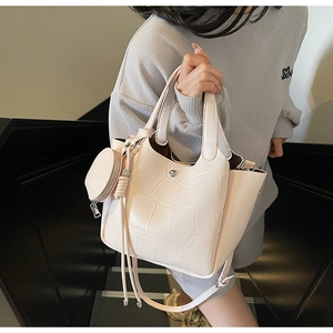 Détail du sac seau rose clair à motif crocodile avec petit charm rond et bandoulière