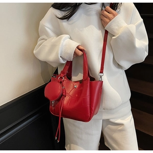 Détail d'un sac seau rouge foncé effet crocodile avec un petit porte-monnaie suspendu
