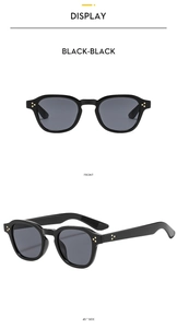 Close-up of retro black sunglasses with gold triple-dot rivets and grey lenses