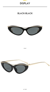 Détail de lunettes de soleil œil-de-chat noires avec bordure dorée et branches fines