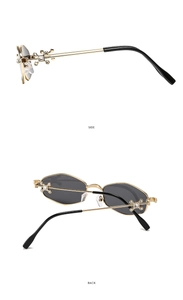 Detail of gold metal sunglasses with side rhinestone cross and hexagonal dark lenses