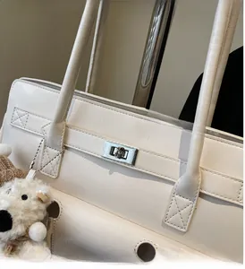 Detail of silver twist lock and textured cream leather on elegant tote bag with charm