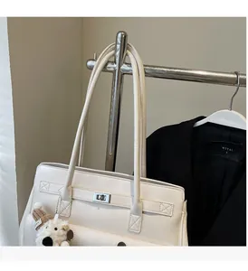 Detail of cream white tote bag featuring a metal twist lock and cute bear charm pendant