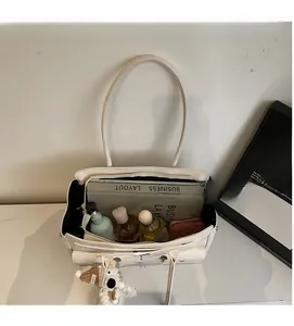 Spacious interior of a cream shoulder bag holding a magazine, wallet, and skincare items