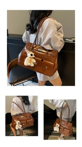 Detail of a brown leather shoulder bag with functional pockets and a plush bear charm