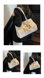 Detail view of large white faux leather tote bag with stylish plush puppy pendant charm