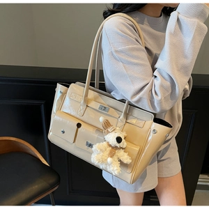 Detail view of cream patent leather tote bag with silver locks and cute plush bear charm