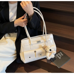 Detail of white PU leather shoulder bag featuring a mini teddy bear charm and metal buckle
