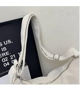 Close-up of white leather tote bag featuring adjustable shoulder strap and silver buckle