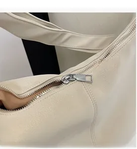Detail shot of a cream tote bag with smooth silver metal zipper and soft textured leather