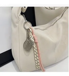 Detail of soft cream tote bag with silver rings and decorative tennis racket keychain