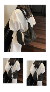 Detail of black tote bag featuring retro pleated leather texture and colorful tassel charm