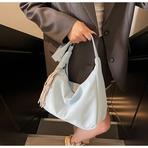 Detail of light blue hobo bag with woven rope charm on a zipper shown on a model