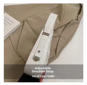 Dettaglio della tracolla regolabile con fibbia argento su borsa bianca motivo coccodrillo