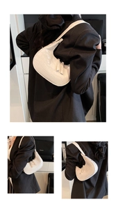 Detailed view of white crocodile pattern hobo bag with zip closure on model