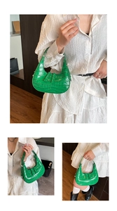 Detail of green crocodile texture on moon-shaped hobo bag with glossy finish handle