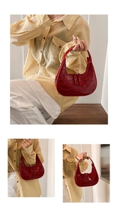 Detail of dark red crocodile pattern dumpling bag with glossy finish and metal zipper