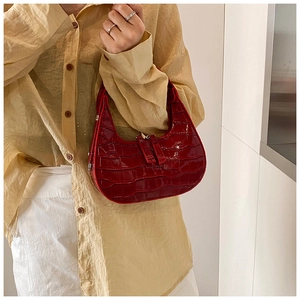 Dettaglio della borsa hobo in similpelle rosso scuro con stampa coccodrillo e finitura lucida