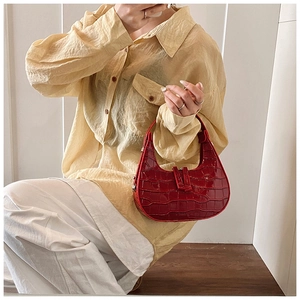Dettaglio della borsa rossa con trama a coccodrillo indossata da una modella indoor