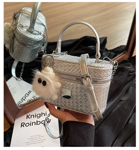 Detail of silver woven texture bucket bag with dual zippers and plush monster charm