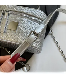 Detail of silver woven crossbody bag showing adjustable leather strap and metallic buckle
