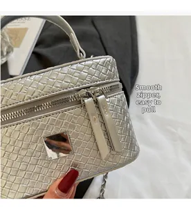 Detail of silver woven texture handbag featuring smooth dual metal zippers and a top handle