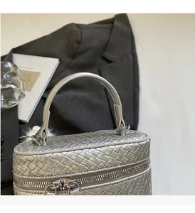 Close-up of silver woven handbag with durable tubular handles and smooth top zipper
