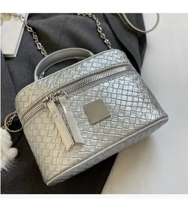Detailed top view of silver woven box bag with chain strap and white pom-pom charm