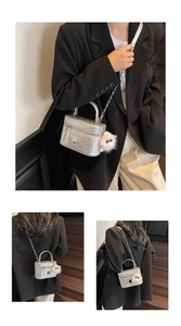 Detail of silver woven vanity bag with metal chain strap and white plush charm