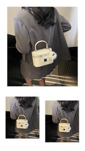 Detail of cream quilted mini box bag with silver chain strap and plush charm