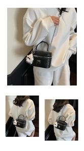 Detail of black woven box bag with silver hardware and white plush charm on leather handle