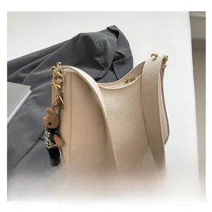 Detail of cream white lychee pattern leather shoulder bag with cute teddy bear pendant