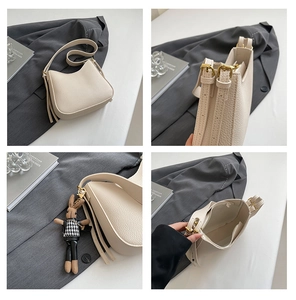 Detail view of beige textured leather bucket bag with tassel and rabbit charm