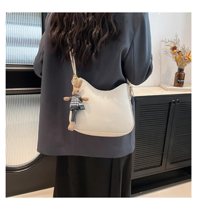 Détail d'un sac hobo beige en cuir grainé avec un charmant pendentif lapin en peluche