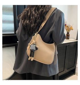 Détail du sac hobo en cuir beige avec franges et charm lapin en peluche sur la bandoulière