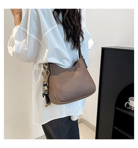 Brown lychee leather hobo bag with a cute rabbit charm shown on model's shoulder