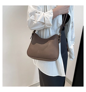 Détail d'un sac à bandoulière en cuir marron motif litchi avec accessoires dorés et sangle