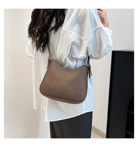 Side view of brown lychee texture leather crossbody bag with adjustable gold buckle strap