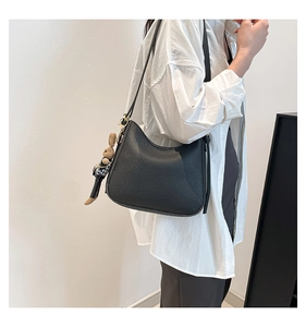 Détail d'un sac hobo en cuir grainé noir avec une décoration de lapin en peluche