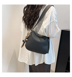 Detail of black lychee grain leather bucket bag with cute bunny pendant and wide strap