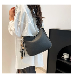 Side view of black pebbled leather hobo bag with a cute plaid teddy bear charm
