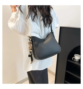 Model wearing a black pebble leather half-moon bucket bag with a cute rabbit charm