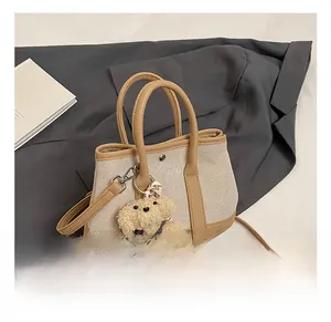 Detail of canvas bucket bag with leather trim and cute teddy bear pendant charm