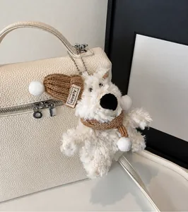Detalle de un lindo colgante de cachorro de peluche con gorro en un bolso de cuero beige