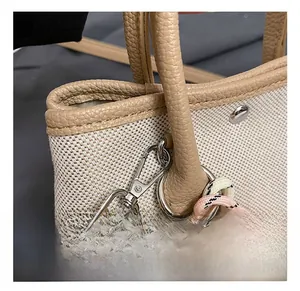 Detail of silver metal hook and leather stitching on canvas bucket bag with bear charm