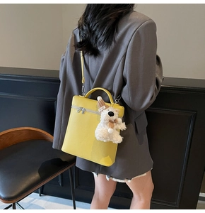 Vista detallada del bolso de mano amarillo con colgante de osito de peluche blanco