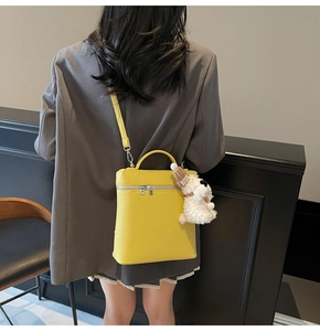 Detalle de bolso de mano amarillo en cuero texturizado con un lindo colgante de perro